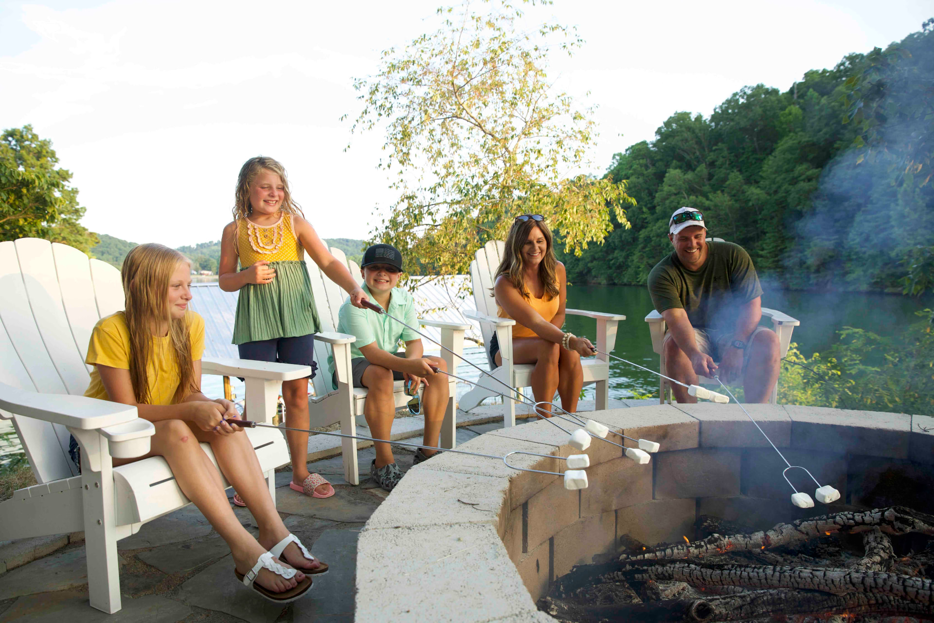 A family roasting marshmallows together by a lakeside fire pit in Roane County, Tennessee