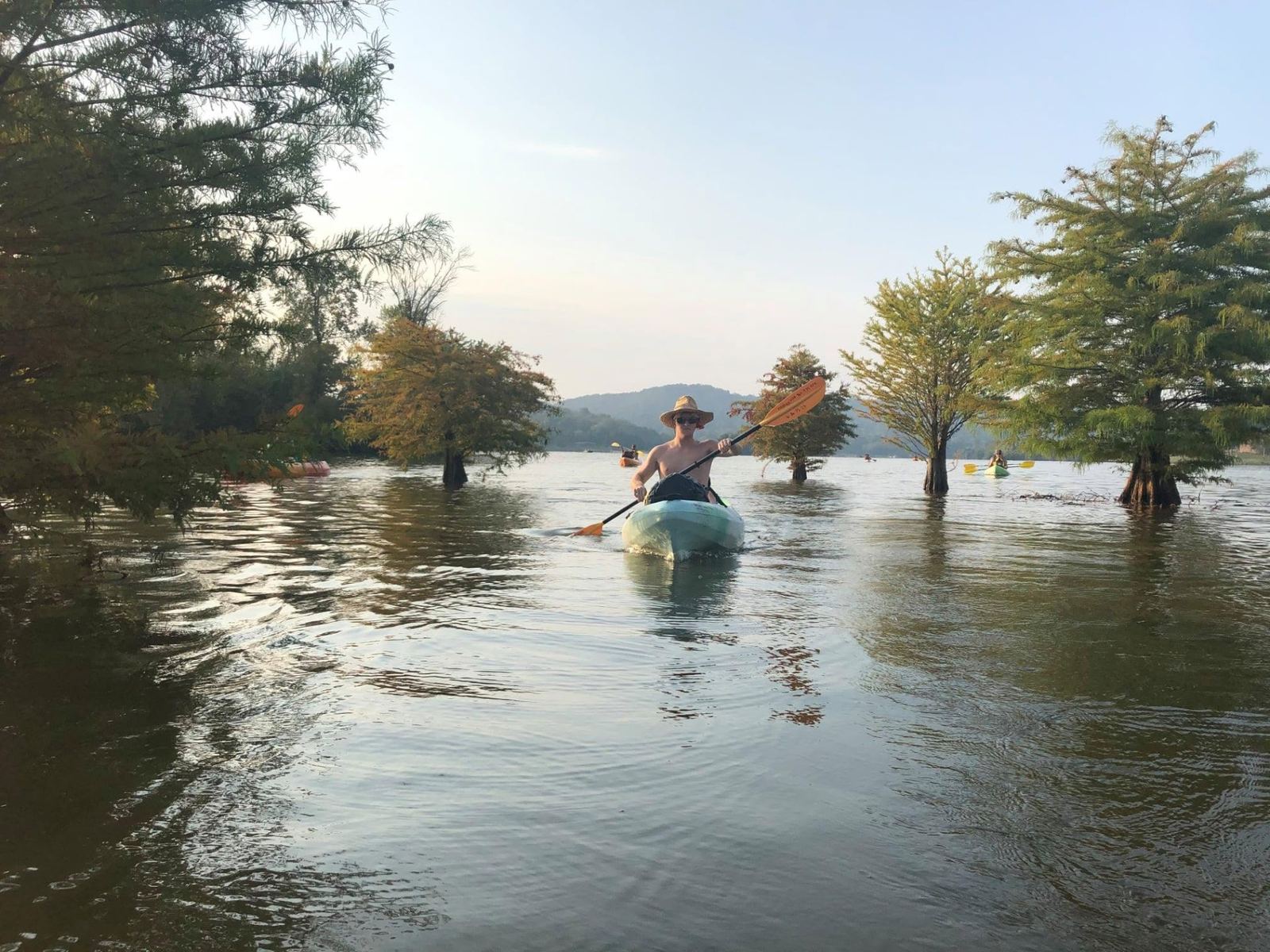 Kayakers paddling on calm Watts Bar Lake at sunrise