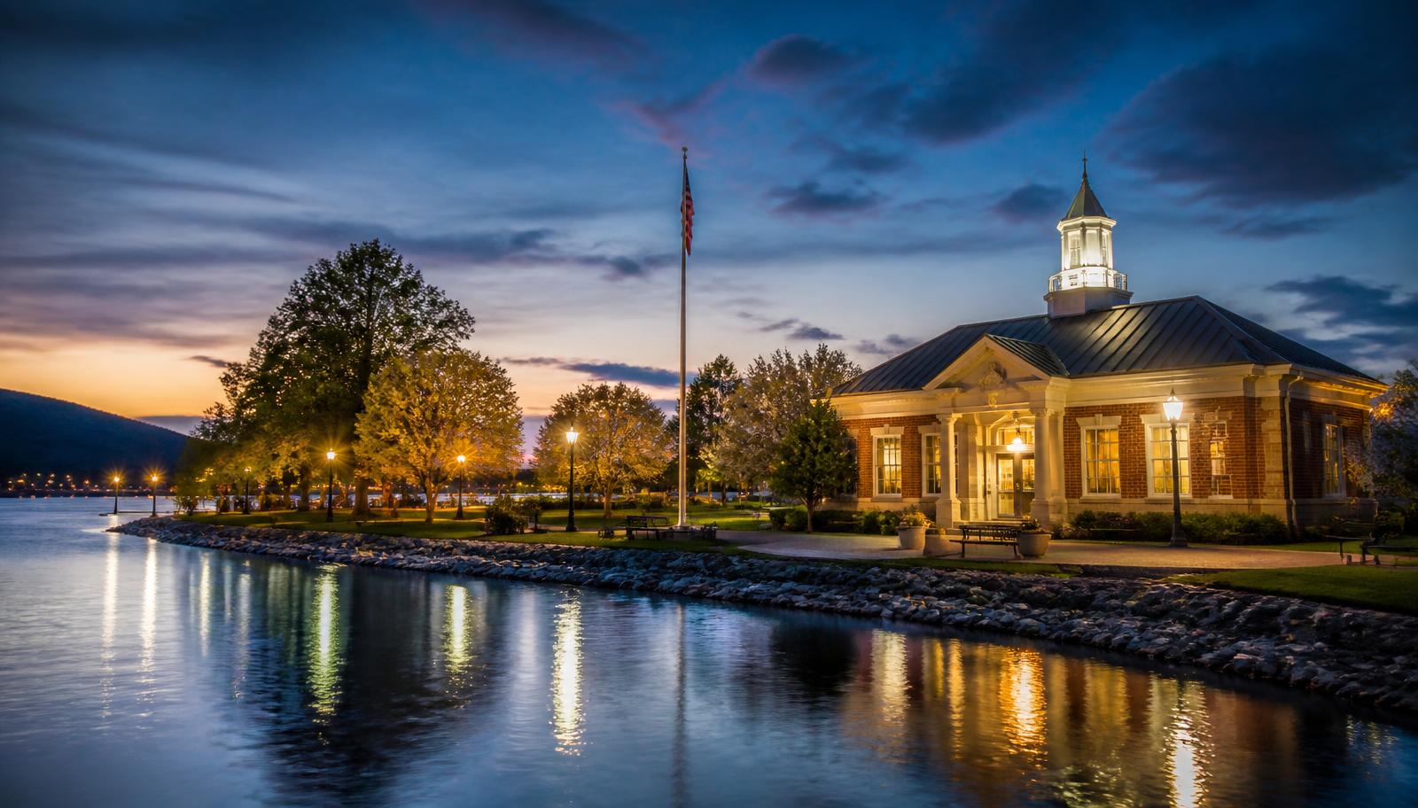 The Kingston, Tennessee waterfront at dusk with a brick civic building lit against a blue-hour sky