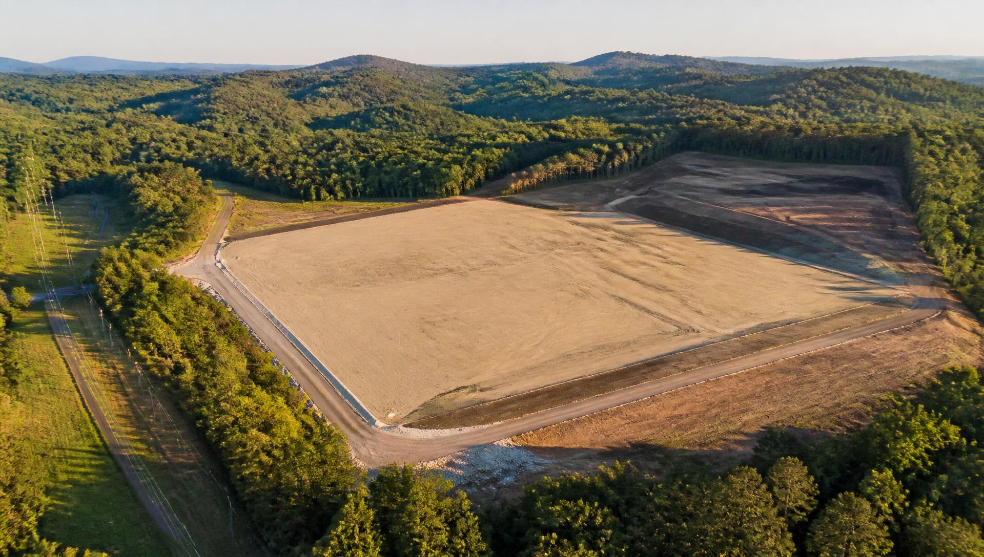 Aerial view of a graded shovel-ready industrial site surrounded by forested East Tennessee hills